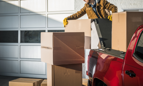 Cardboard boxes being stacked into the back of a pickup truck.